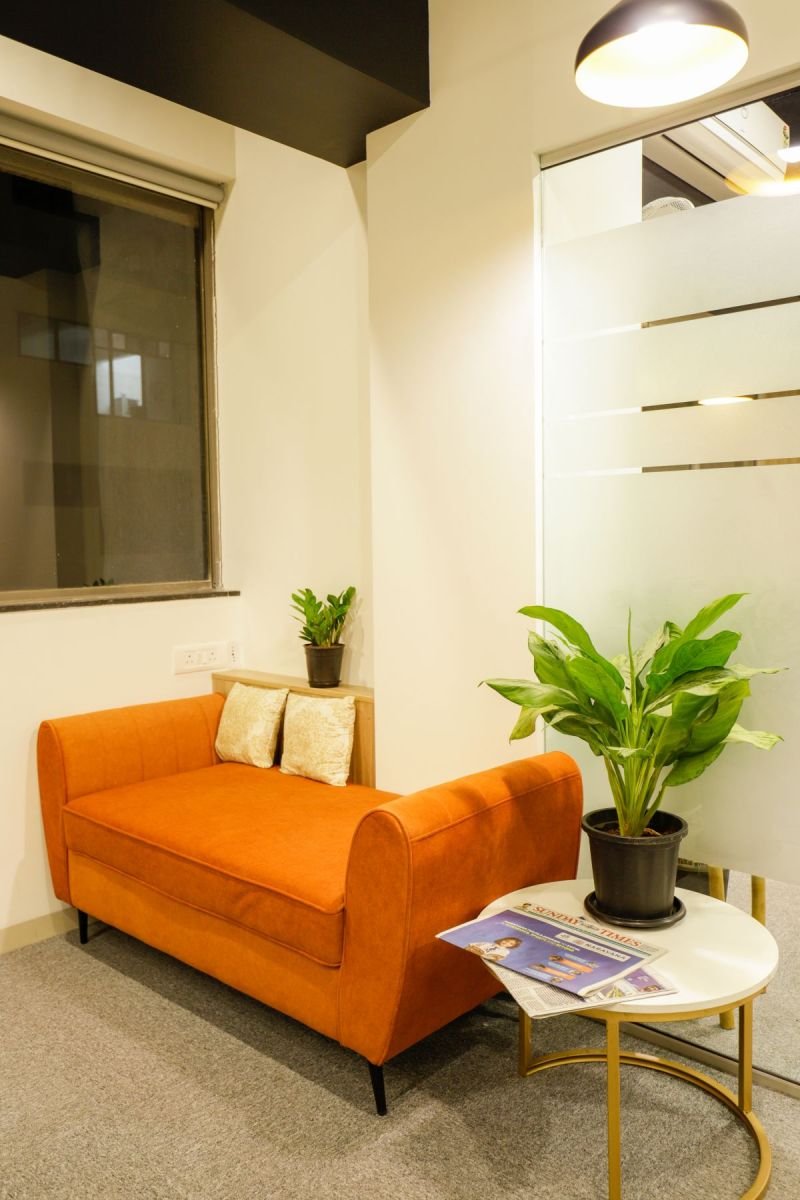 Waiting lounge with orange sofa, managed office built by Workin Space